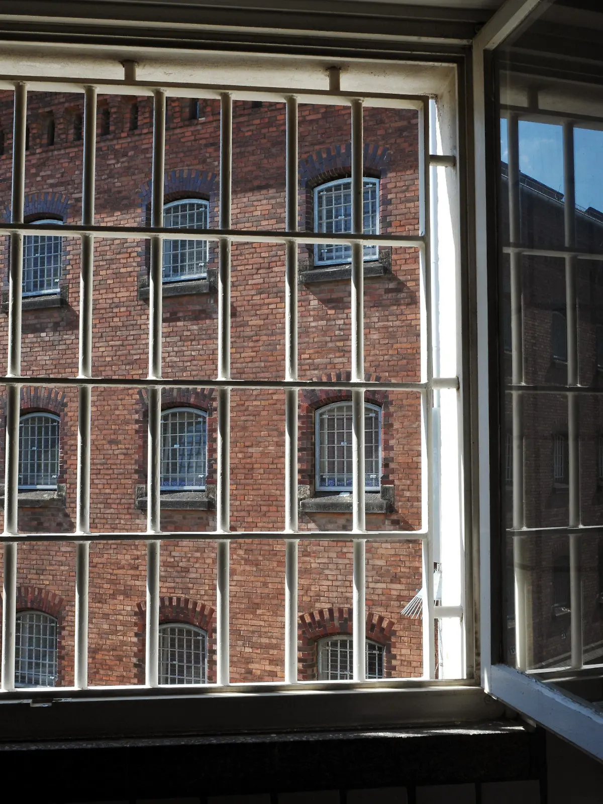 Offen steht am Mittwoch (07.07.2010) ein vergittertes Fenster der JVA-Klinik in Kassel und gibt den Blick frei auf einen Gefängnisflügel der JVA Kassel I. Rechts spiegelt sich der Sommerhimmel. Schweißtreibend ist das Sommerwetter auch für die Gefängnisinsassen. Die Temperaturen steigen bis zum Wochenende wieder auf Werte um die 35 Grad und darüber. Foto: Uwe Zucchi dpa/lhe  +++(c) dpa - Bildfunk+++
