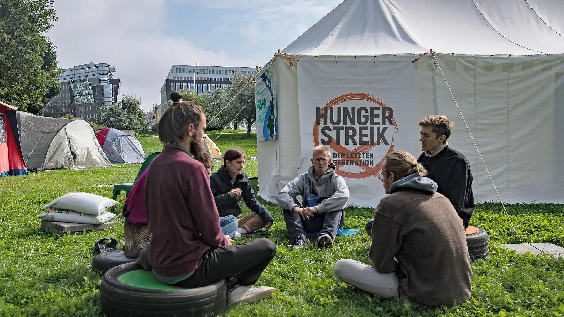 02.09.2021, Berlin: Umweltaktivisten sitzen im Regierungsviertel zusammen vor einem Zelt. Seit Tagen befinden sich die jungen Menschen in einem Hungerstreik. Sie wollen mit der Aktion zwei Ziele erreichen, wie eine Sprecherin mitteilt. Zum einen wollen sie ein Gespräch mit den drei Spitzenkanidaten bei der anstehenden Bundestagswahl. Ausserdem wollen sie von den Politikern eine Zusage haben, dass mit der neuen Legislaturperiode ein Rat eingerichtet wird, in dem die künftige Klimapolitik festgelegt wird. Foto: Paul Zinken/dpa +++ dpa-Bildfunk +++