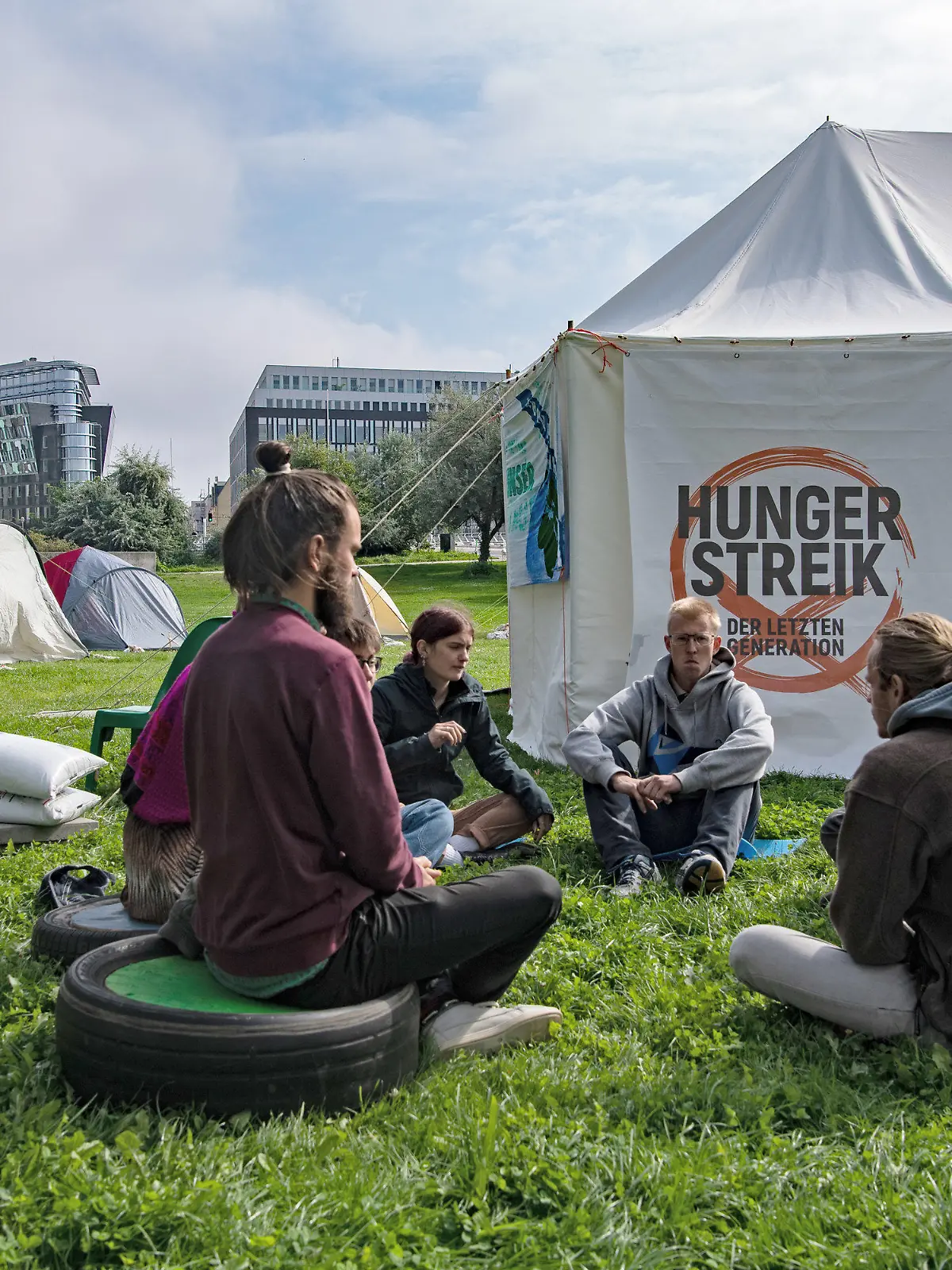 02.09.2021, Berlin: Umweltaktivisten sitzen im Regierungsviertel zusammen vor einem Zelt. Seit Tagen befinden sich die jungen Menschen in einem Hungerstreik. Sie wollen mit der Aktion zwei Ziele erreichen, wie eine Sprecherin mitteilt. Zum einen wollen sie ein Gespräch mit den drei Spitzenkanidaten bei der anstehenden Bundestagswahl. Ausserdem wollen sie von den Politikern eine Zusage haben, dass mit der neuen Legislaturperiode ein Rat eingerichtet wird, in dem die künftige Klimapolitik festgelegt wird. Foto: Paul Zinken/dpa +++ dpa-Bildfunk +++
