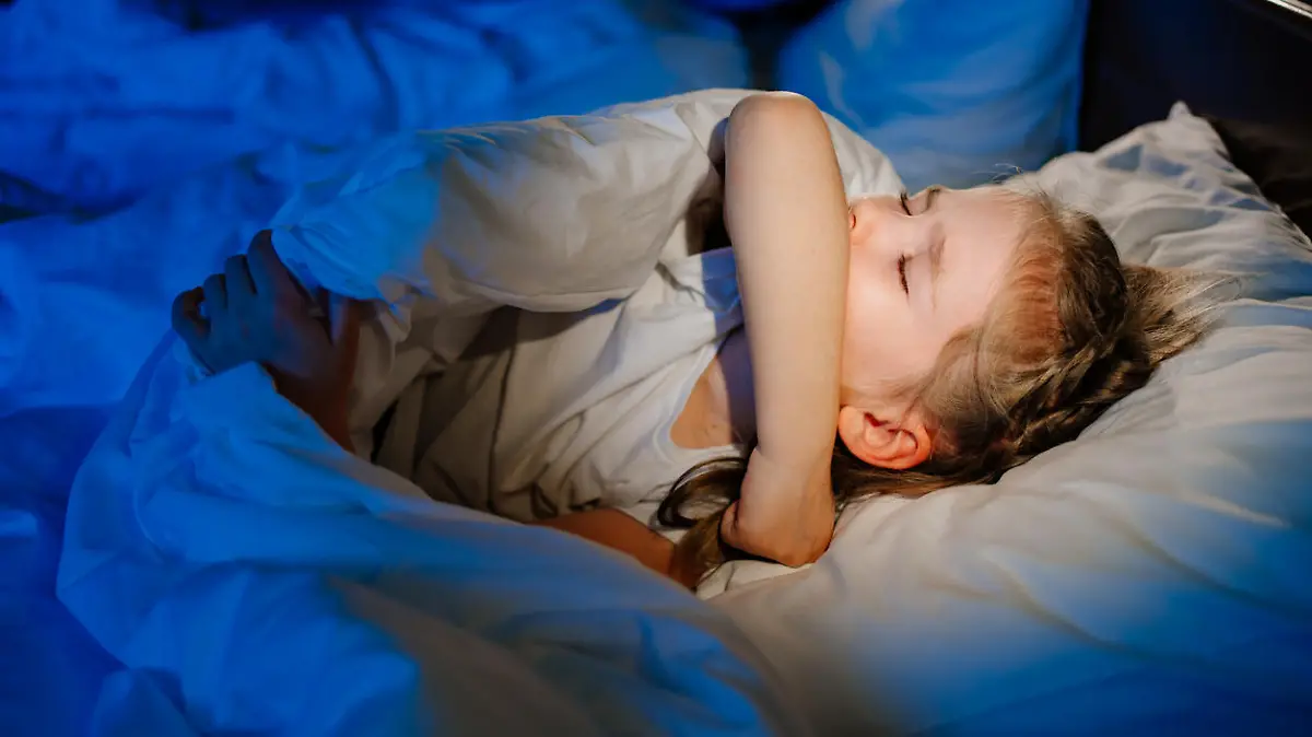 The little girl is sick, lies in bed and coughs. caring for children. restless sleep during illness. cough medicine.