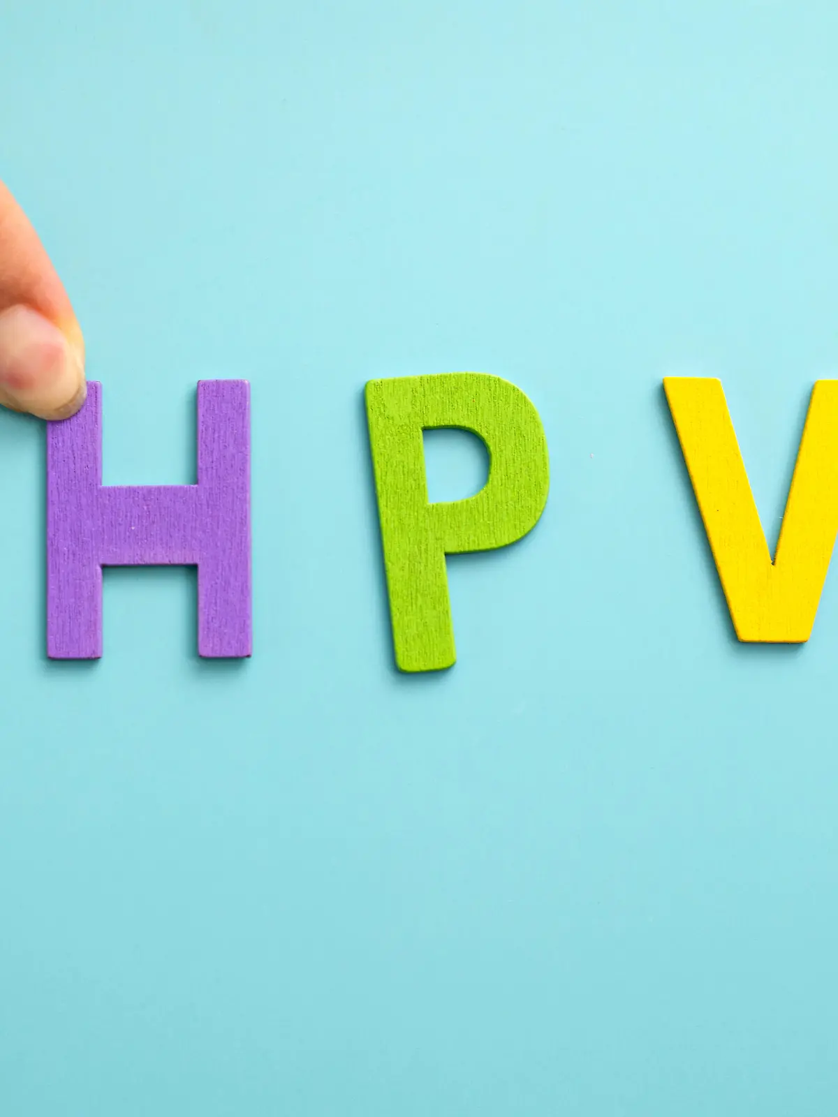 Flat lay multicolor wooden alphabet words "HPV" on blue background