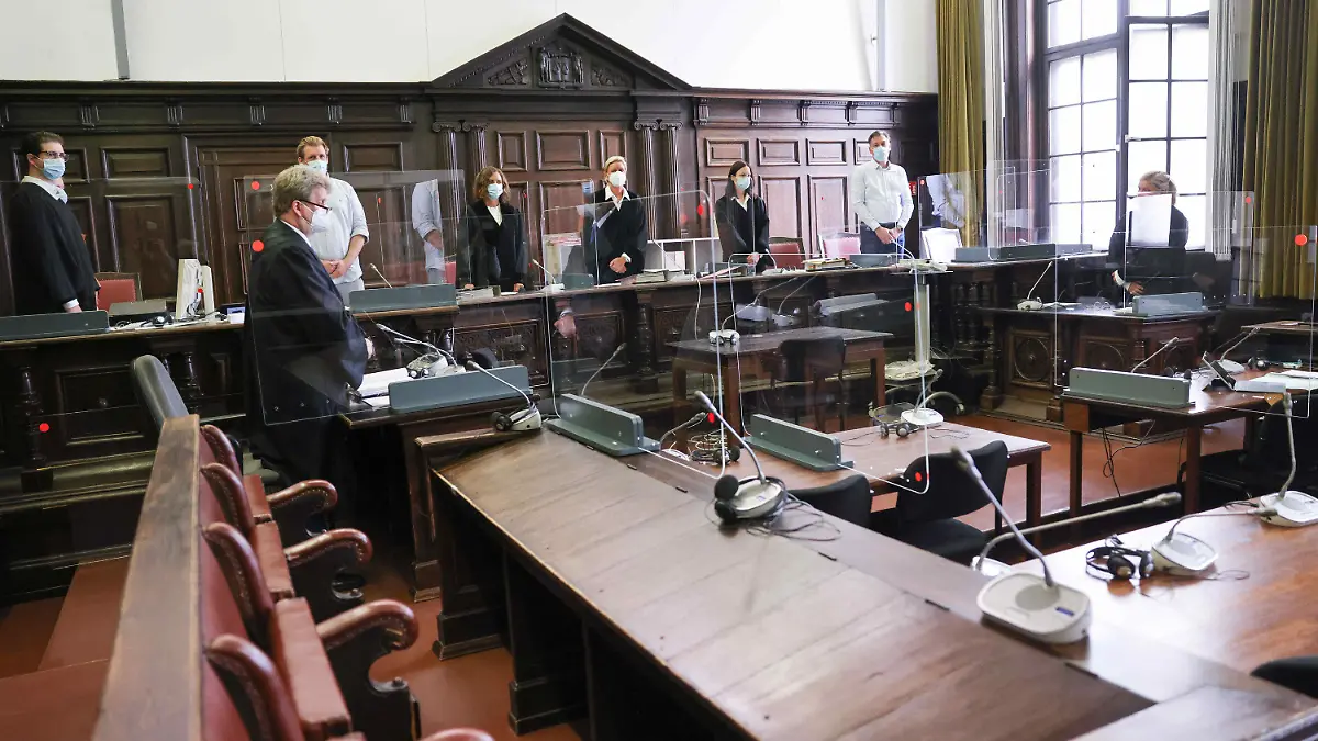 ARCHIV - 03.08.2021, Hamburg: Jessica Koerner (5.v.l), Vorsitzende Richterin am Landgericht, Peter Jacobi (2.v.l), Anwalt des Beschuldigten, und weitere Prozessbeteiligte stehen zu Beginn des ersten Prozesstages im Sitzungssal im Strafjustizgebäude. Der Beschuldigte soll Anfang Februar 2021 seine damalige Lebensgefährtin tödlich verletzt und am Folgetag seine Mutter mit zahlreichen Messerstichen umgebracht haben. Der 29-Jährige ist nach Auffassung der Staatsanwaltschaft psychisch krank und darum schuldunfähig. (zu dpa: «Freundin und Mutter getötet - Plädoyers im Prozess erwartet») Foto: Christian Charisius/dpa-Pool/dpa +++ dpa-Bildfunk +++