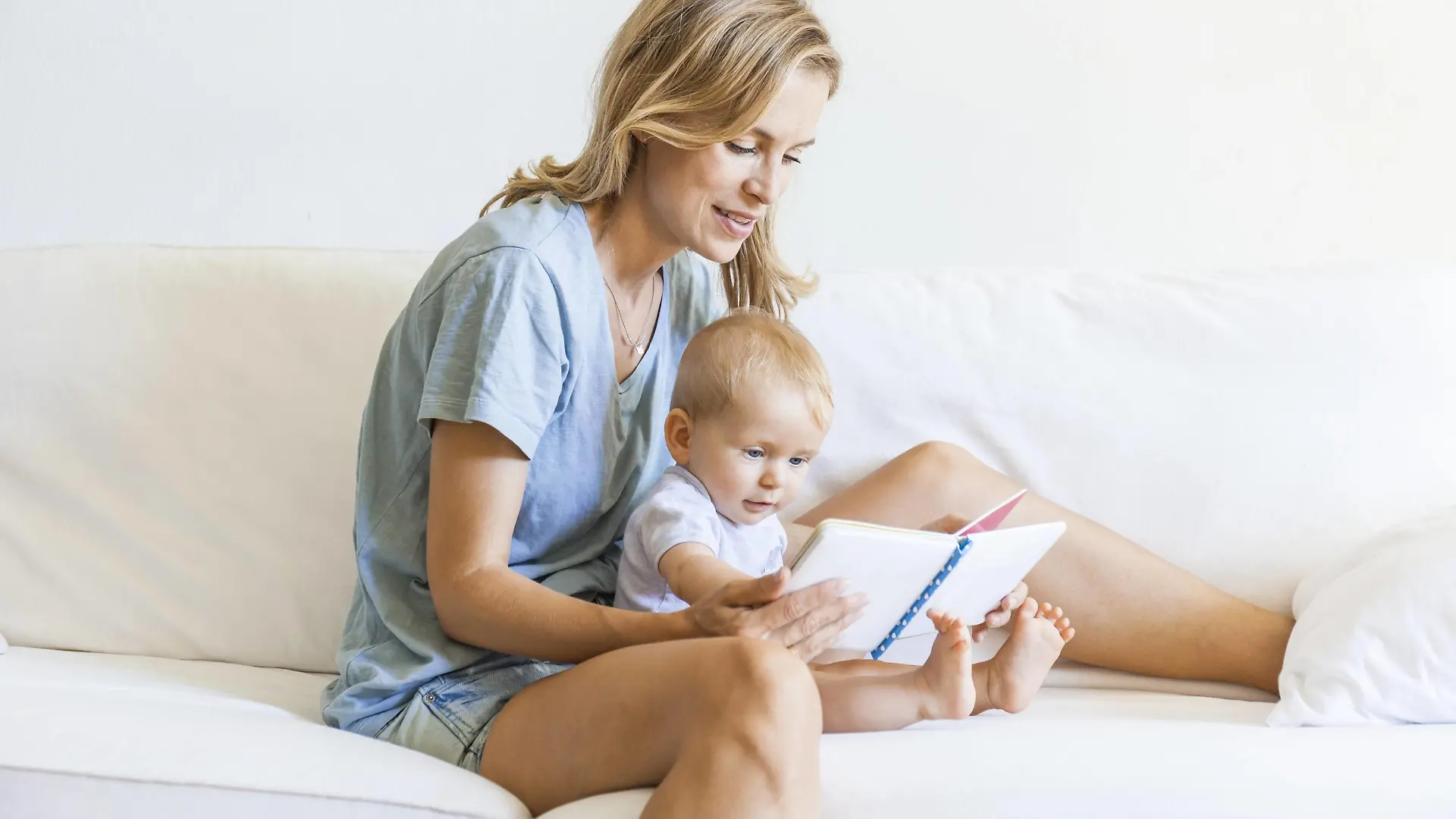 Mother and baby girl sitting on couch looking at picture book model released Symbolfoto property released PUBLICATIONxINxGERxSUIxAUTxHUNxONLY TCF05872  