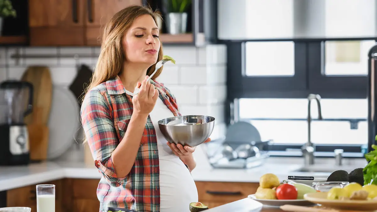 Young beautiful pregnant woman preparing healthy meal with fruites and vegetables