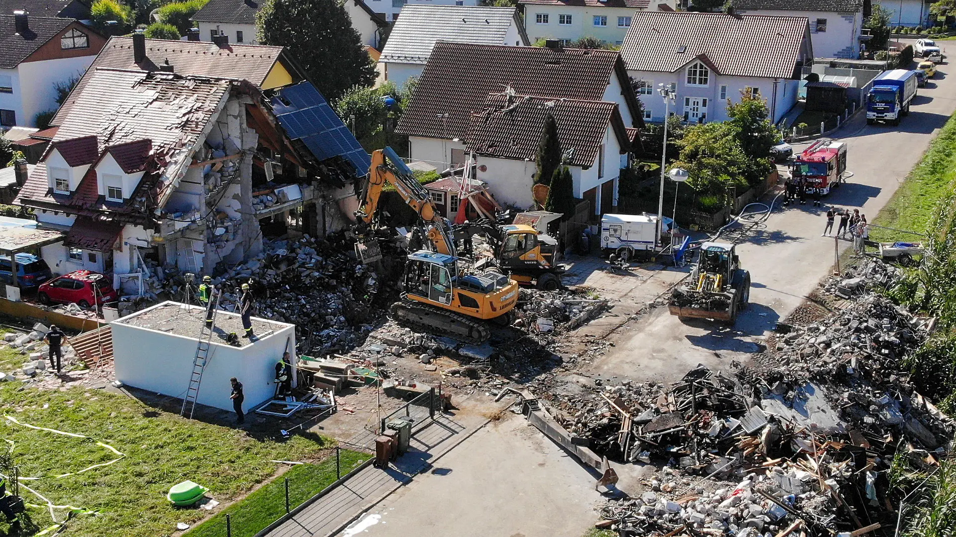 03.09.2021, Bayern, Rohrbach: Zwei Bagger und ein Radlader sind bei Bergungsarbeiten an den Überresten eines Hauses im Einsatz, das am Donnerstag (02.09.2021) durch eine Explosion vollständig zerstört wurde (Aufnahme mit einer Drohne). Daneben steht das stark beschädigte Nachbarhaus. Bei dem Unglück waren zwei Menschen in dem Nachbarhaus leicht verletzt worden. Zwei Menschen aus dem zerstörten Haus werden noch vermisst. Foto: Vifogra/dpa +++ dpa-Bildfunk +++