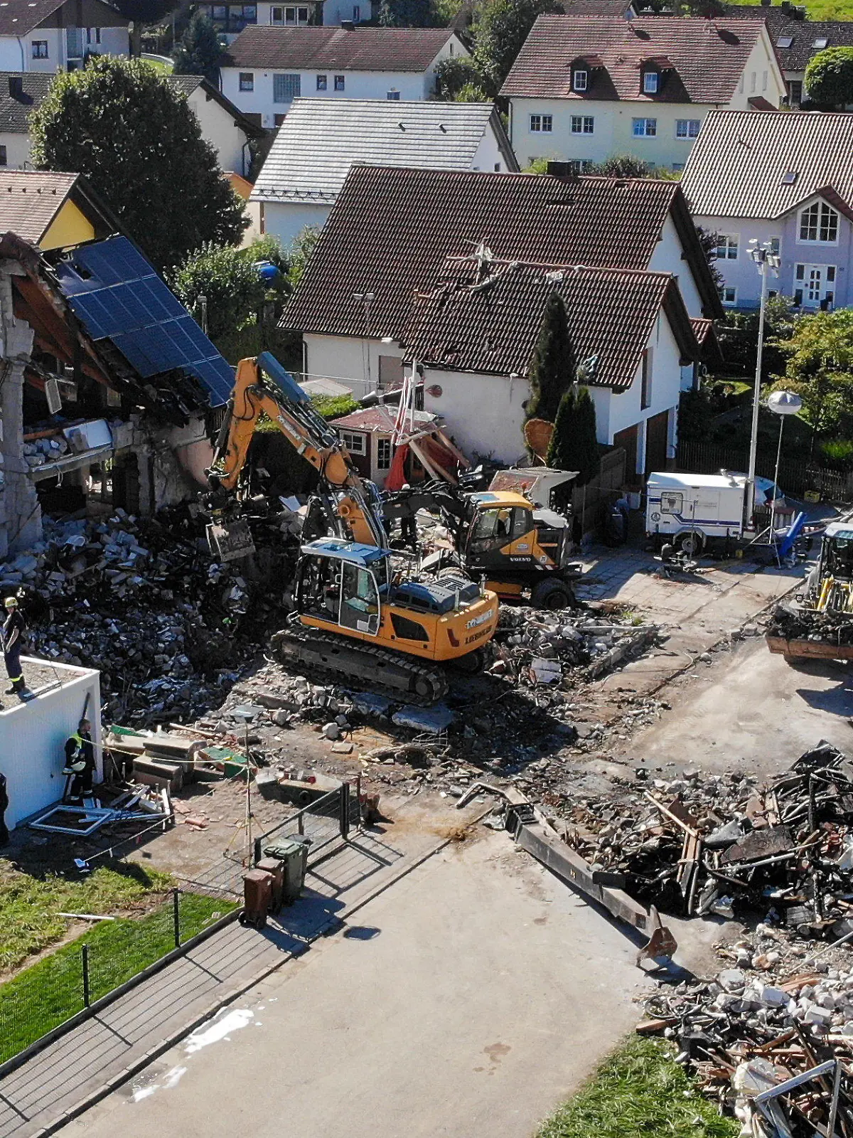 03.09.2021, Bayern, Rohrbach: Zwei Bagger und ein Radlader sind bei Bergungsarbeiten an den Überresten eines Hauses im Einsatz, das am Donnerstag (02.09.2021) durch eine Explosion vollständig zerstört wurde (Aufnahme mit einer Drohne). Daneben steht das stark beschädigte Nachbarhaus. Bei dem Unglück waren zwei Menschen in dem Nachbarhaus leicht verletzt worden. Zwei Menschen aus dem zerstörten Haus werden noch vermisst. Foto: Vifogra/dpa +++ dpa-Bildfunk +++