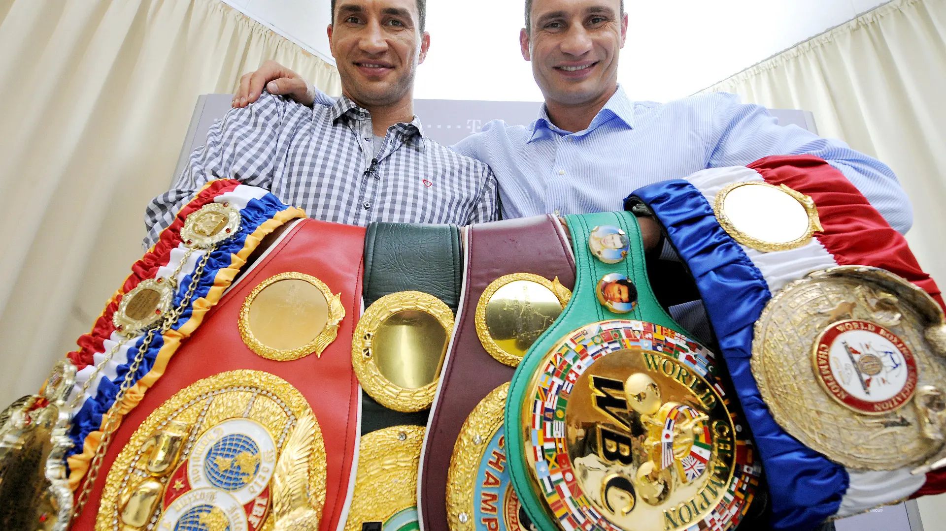 Die Schwergewichtsboxer Wladimir und Vitali (r) Klitschko aus der Ukraine halten am Dienstag (05.07.2011) in einem Hotel in Hamburg- Bergedorf ihre Weltmeistergürtel im Anschluß an eine Video-Pressekonferenz. Die Video-Pressekonferenz findet gleichzeitig in sechs Städten in Deutschland statt. Wladimir ist WBA-, WBO- und IBF-Weltmeister, Vitali hält den Titel nach WBC-Version. Foto: Christian Charisius dpa/lno +++(c) dpa - Bildfunk+++