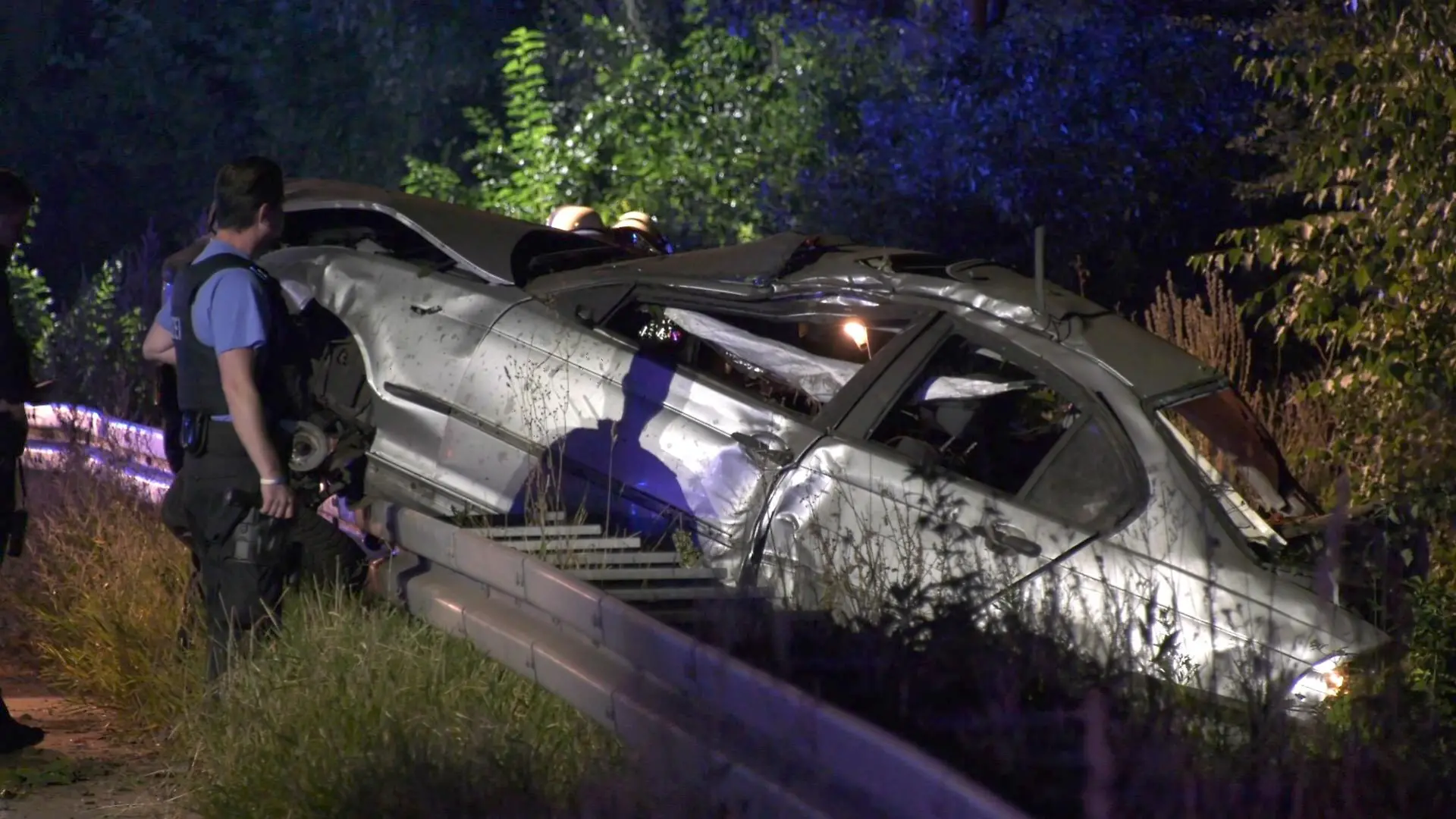 06.09.2021, Hessen, Rüsselsheim: Ein Polizist untersucht das Wrack eines PKW. Am Autobahndreieck Rüsselsheim ist ein Mann von einem Lastwagen überfahren und tödlich verletzt worden. Der Autofahrer wurde zuvor aus seinem Auto geschleudert, wie ein Polizeisprecher am Montag mitteilte. Polizeibeamten fanden das Auto des Mannes in der Nacht auf der Leitplanke der A67 auf Höhe des Autobahnkreuzes. Foto: -/Keutz TV/dpa +++ dpa-Bildfunk +++