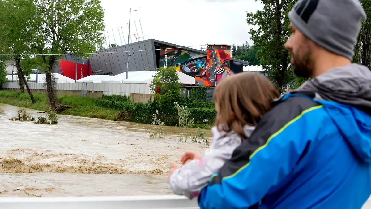 A man holding a child looks at the swollen Santerno River with behind the Enzo e Dino Ferrari circuit, in Imola, Italy, Wednesday, May 17, 2023. The weekend's Emilia-Romagna Grand Prix in Imola has been canceled because of deadly floods. Formula One said it made the decision for safety reasons and to avoid any extra burden on the emergency services. F1 personnel had earlier been told to stay away from the track after floods affected large parts of the Emilia-Romagna region. (AP Photo/Luca Bruno)