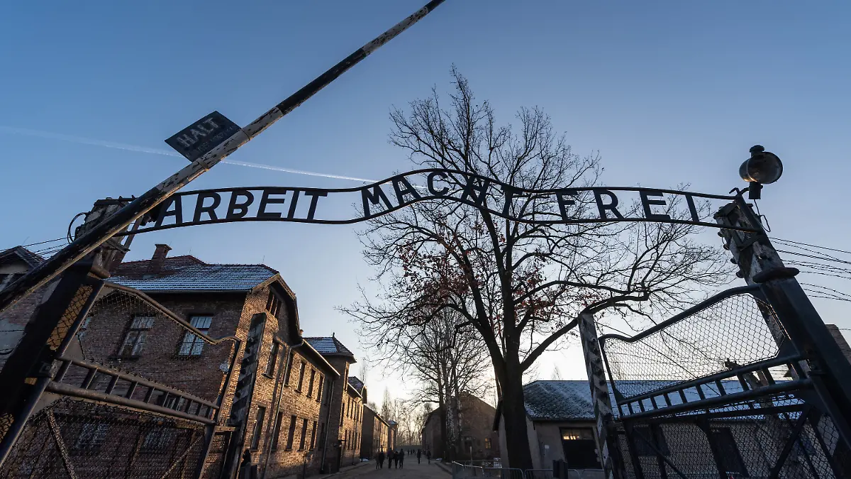 Blick auf das Eingangstor des ehemaligen deutschen Konzentrationslagers Auschwitz mit dem Schriftzug „Arbeit macht frei”