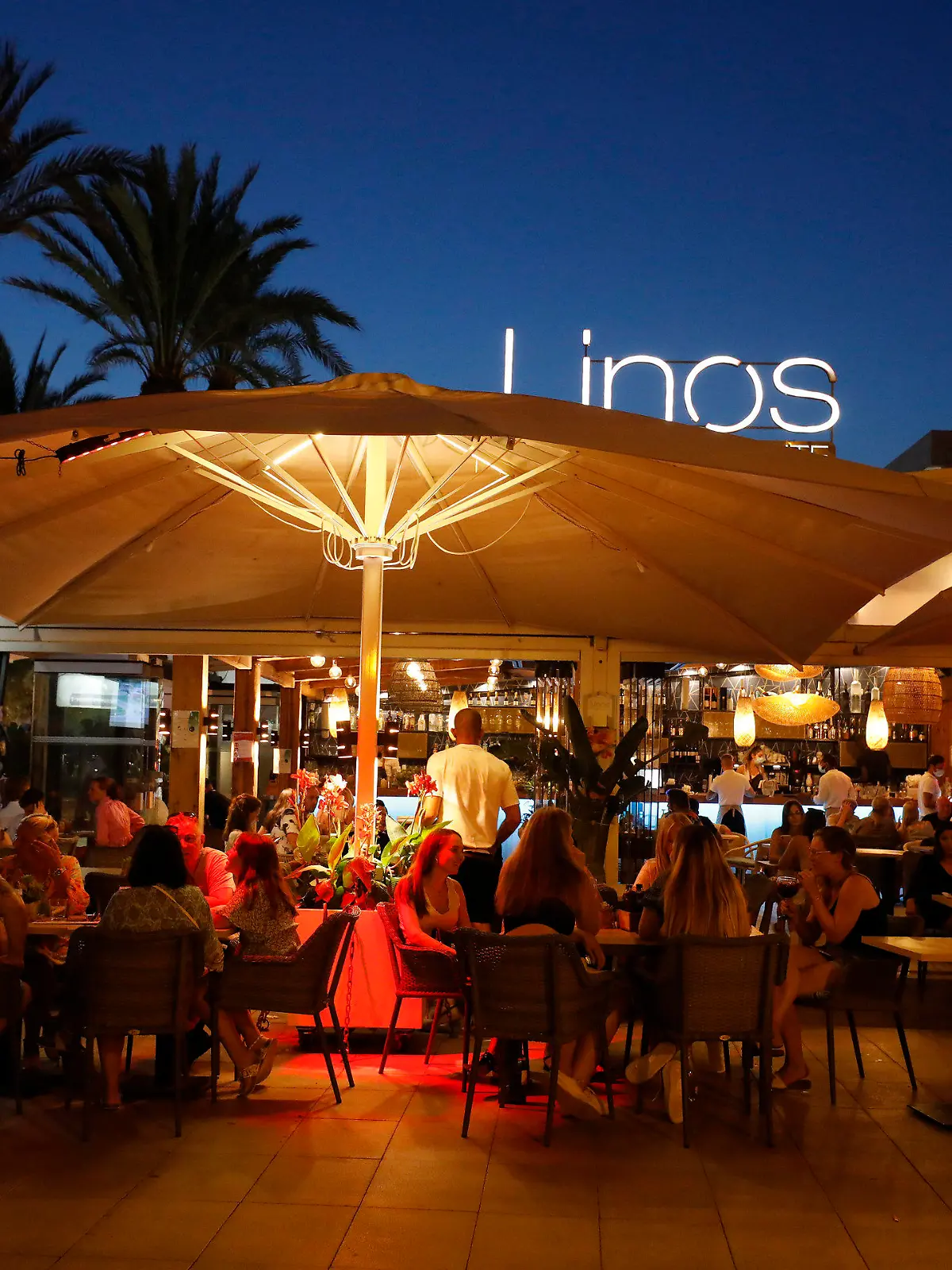 ARCHIV - 22.07.2021, Spanien, Palma de Mallorca: Menschen sitzen in einer Bar an der Strandpromenade von Palma. Angesichts fallender Corona-Zahlen werden die Corona-Restriktionen auf der bei Deutschen beliebten Urlauberinsel Mallorca weiter gelockert. Ab 07.09.2021 dürfen wieder Personen aus verschiedenen Haushalten zu nächtlichen Partys zusammenkommen, teilte die Regionalregierung mit. (zu dpa "Mallorca lockert Corona-Regeln: Nächtliche Partys wieder erlaubt") Foto: Clara Margais/dpa +++ dpa-Bildfunk +++