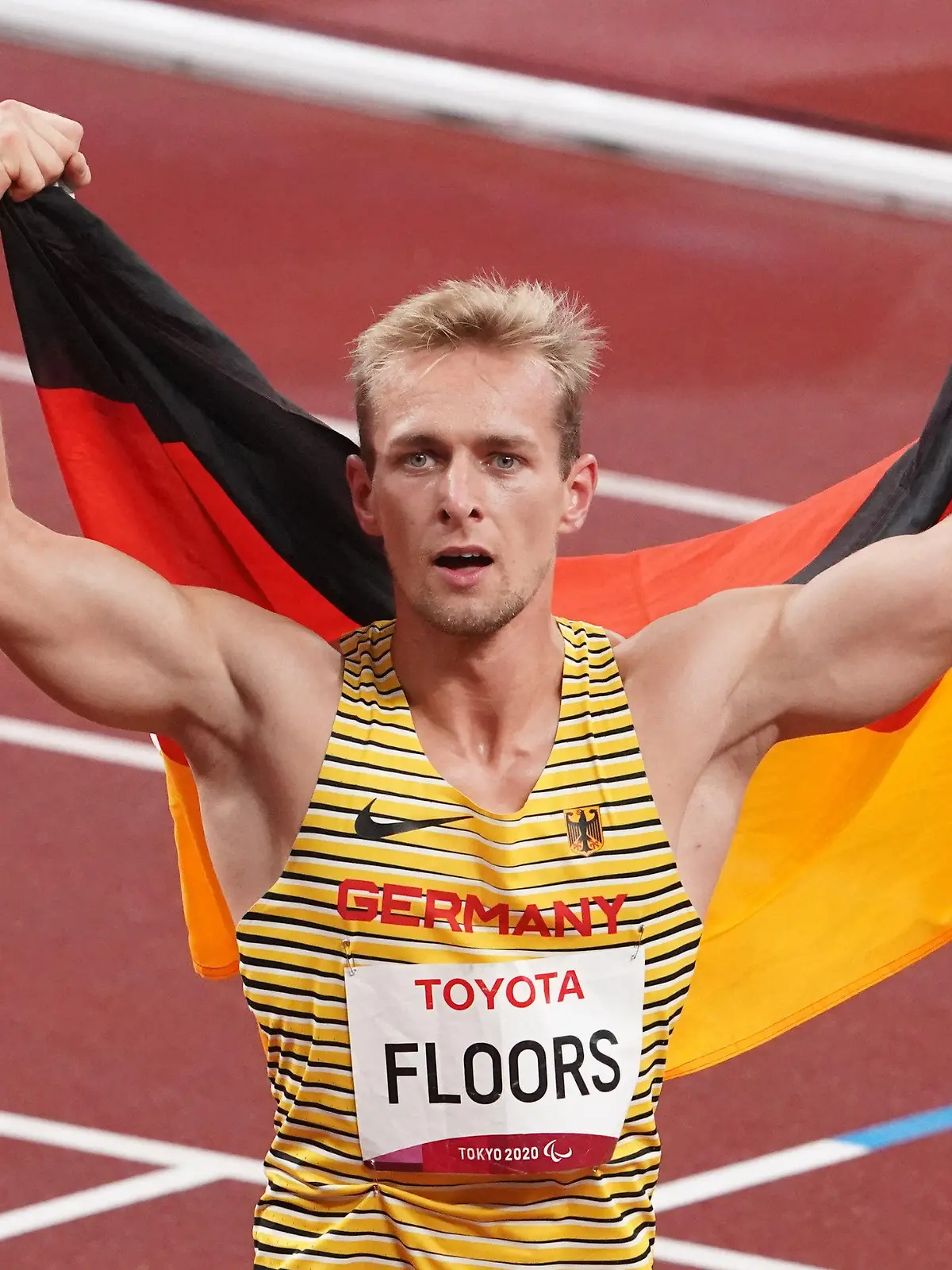 03.09.2021, Japan, Tokio: Paralympics: Leichtathletik, 400 Meter Männer, T62 Finale, im Olympiastadion. Goldmedaillen-Gewinner Johannes Floors aus Deutschland jubelt nach seinem Sieg und neuem Weltrekord mit einer Deutschlandfahne auf den Schultern. (zu dpa "Zielsichere Hiltrop, Raser Floors: Die Gesichter der Paralympics") Foto: Marcus Brandt/dpa +++ dpa-Bildfunk +++