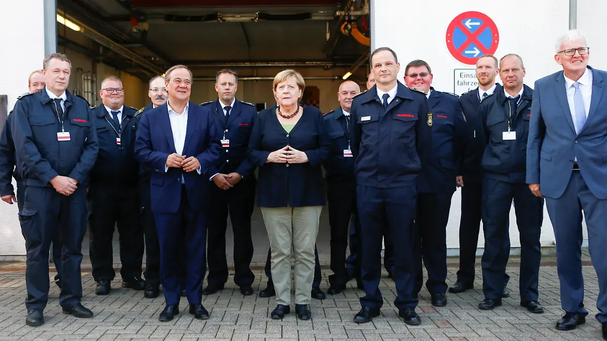 05.09.2021, Nordrhein-Westfalen, Schalksmühle: Bundeskanzlerin Angela Merkel (CDU) und Armin Laschet (5.v.l), Kanzlerkandidat der Union und Vorsitzender der CDU, stehen mit Feuerwehrleuten für ein Foto zusammen. Merkel hat am Sonntag in Schalksmühle im Sauerland Kollegen zweier im Hochwasser-Einsatz gestorbener Feuerwehrleute getroffen. Foto: Thilo Schmuelgen/Reuters Pool/dpa +++ dpa-Bildfunk +++