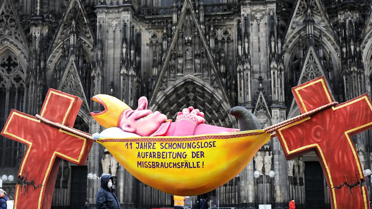 17.03.2021, Nordrhein-Westfalen, Köln: Die Plastik des Künstlers Jacques Tilly mit dem Slogan «11 Jahre schonungslose Aufarbeitung der Missbrauchsfälle!» steht vor dem Kölner Dom. Verschiedene Initiativen, die sich mit der Aufarbeitung des sexuellen Missbrauchs von Kindern durch Priester in der katholischen Kirche befassen, haben sich einen Tag vor der Veröffentlichung des neuen Missbrauchsgutachtens im Erzbistum Köln zu einer Protestveranstaltung vor dem Dom zusammengefunden. Foto: Oliver Berg/dpa - ACHTUNG: Nur zur redaktionellen Verwendung im Zusammenhang mit einer Berichterstattung über den Protest vor dem Kölner Dom mit Nennung des Künstlers und nur mit vollständiger Nennung des vorstehenden Credits +++ dpa-Bildfunk +++