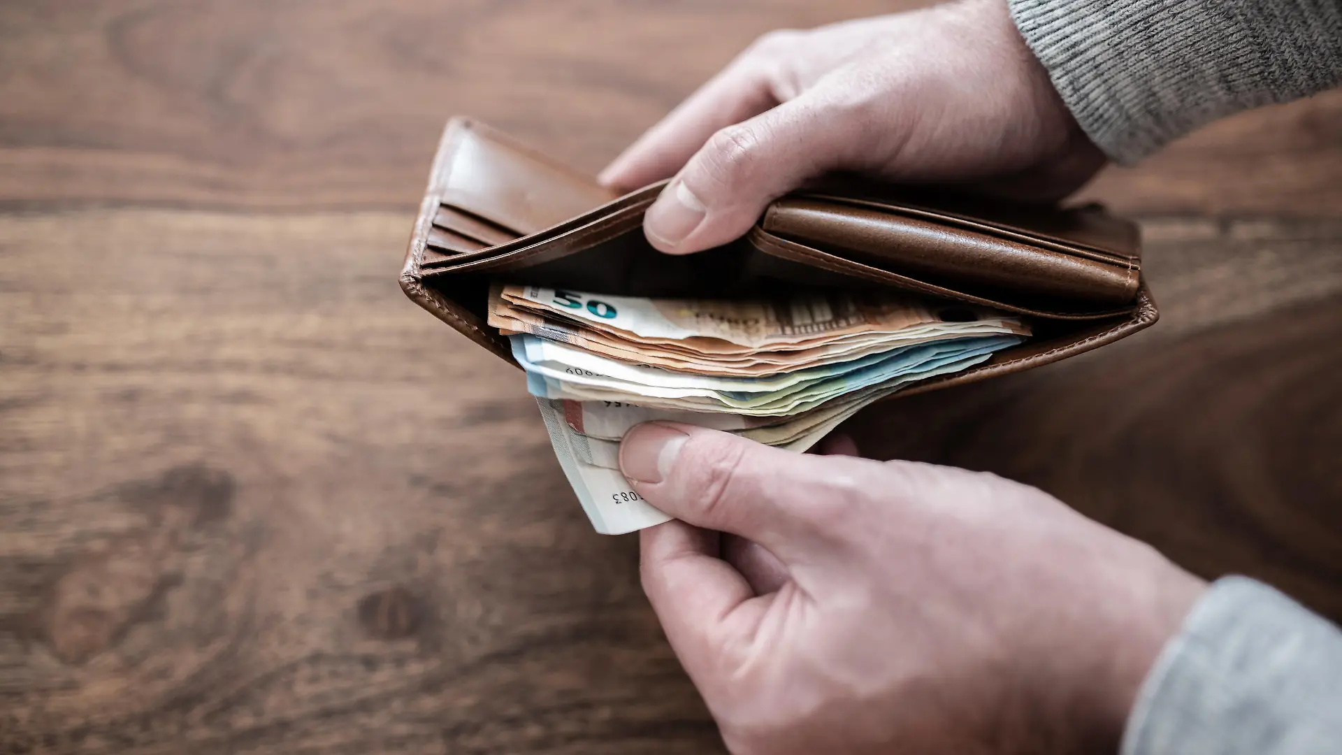 close-up of person counting stack of paper cash in wallet