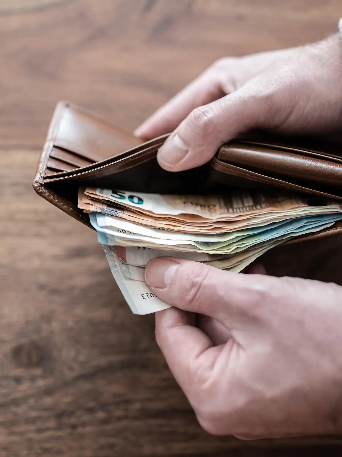 close-up of person counting stack of paper cash in wallet