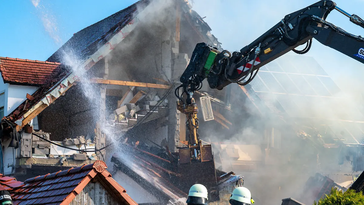 02.09.2021, Bayern, Rohrbach: Ein Bagger räumt Teile des eingestürzten Hauses ab und Einsatzkräfte der Feuerwehr sind in der Nähe eines Hauses im Einsatz, in dem es zuvor nach Angaben der Polizei eine Explosion gegeben hatte. Foto: Armin Weigel/dpa +++ dpa-Bildfunk +++