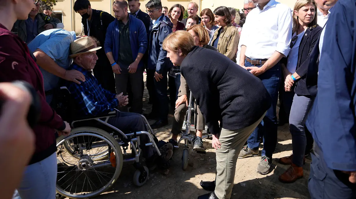 German Chancellor Angela Merkel, center, talks to an elderly man at a retirement home during their visit to the flood-damaged Altenahr, Germany, Friday, Sept. 3, 2021. After days of extreme downpours causing devastating floods hit the valley of the river Ahr in July. (AP Photo/Markus Schreiber, Pool)