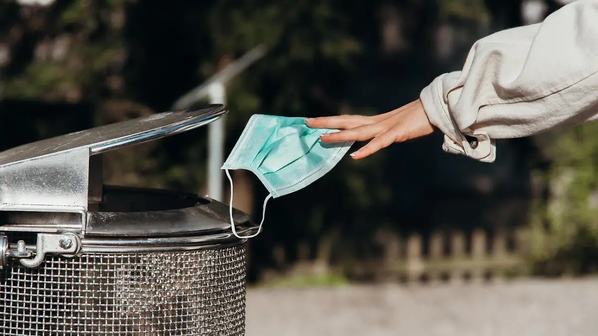 person throws a protective mask into the trash can