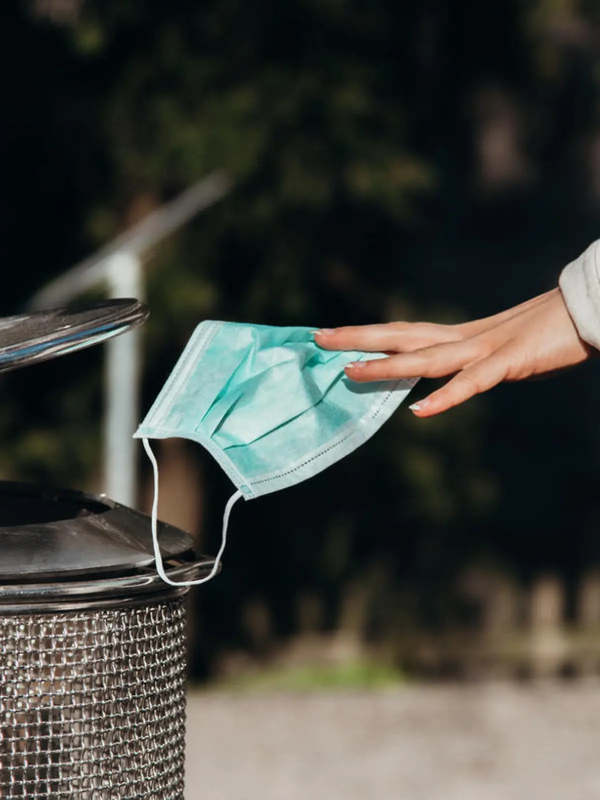 person throws a protective mask into the trash can