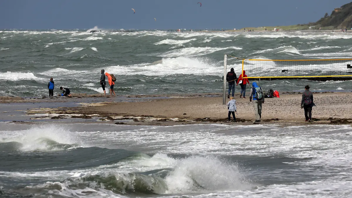 17.08.2021, Mecklenburg-Vorpommern, Wustrow: Spaziergänger sind auf der Halbinsel Fischland an der aufgewühlten Ostsee unterwegs. Kühl, regnerisch und windig ist das Wetter im Norden, stürmische Böen bis Stärke 10 werden erwartet. Foto: Bernd Wüstneck/dpa-Zentralbild/dpa +++ dpa-Bildfunk +++