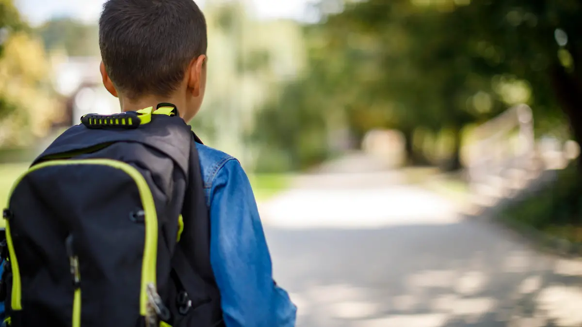 Teenage boy with school bag going home from school
