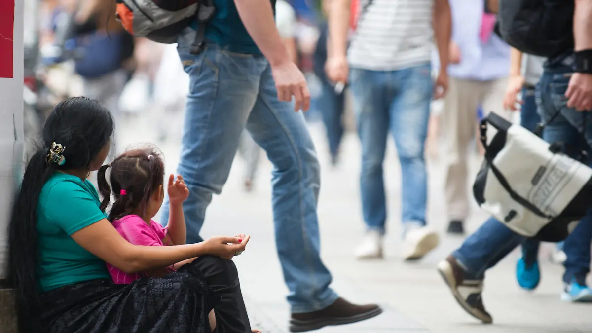 Eine Frau und ein Kind sitzen am 08.07.2015 in Berlin auf einem Bürgersteig und betteln um Geld. Foto: Paul Zinken/dpa (zu dpa «Die bettelnden Kinder von Berlin» vom 23.07.2015) +++(c) dpa - Bildfunk+++