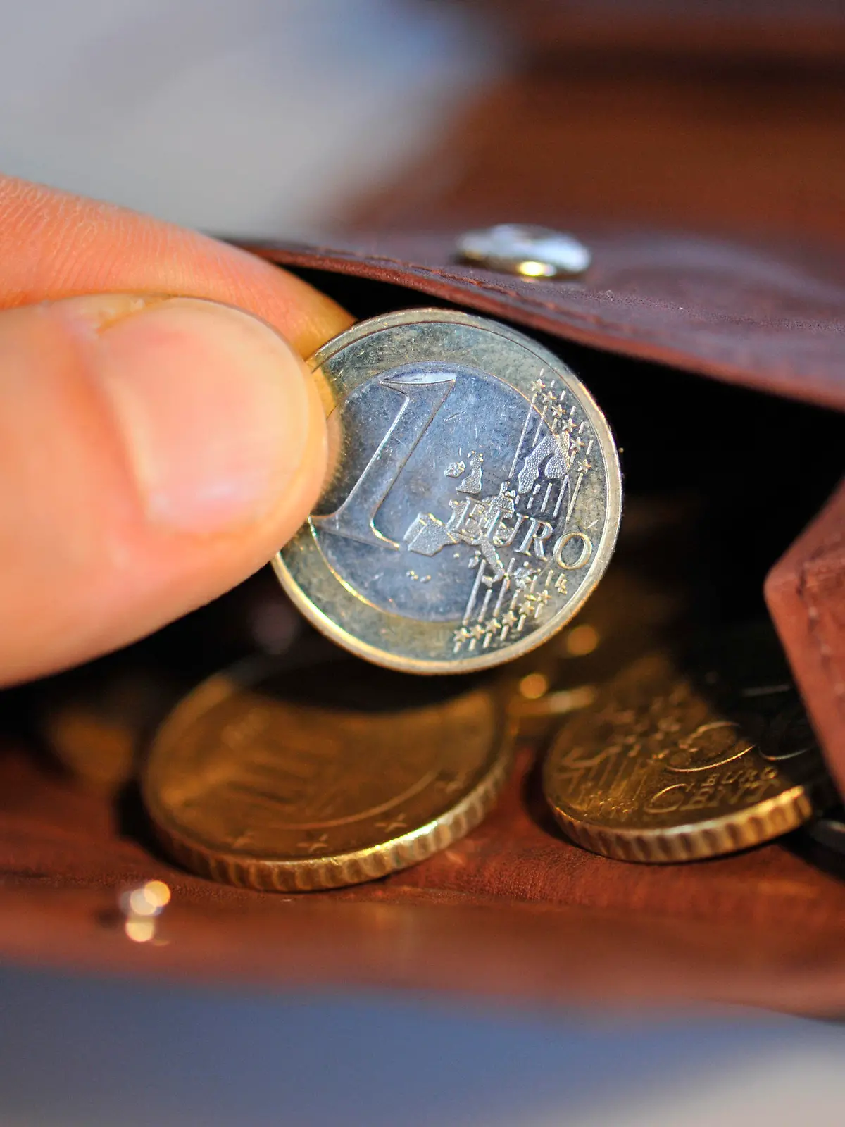 ARCHIV - ILLUSTRATION - Eine Hand nimmt am 22.01.2010 eine Euro-Münze aus einem Geldbörse, in dem sich weitere Münzen befinden. Mehrarbeit lohnt sich für Geringverdiener nicht immer. (zu dpa «Studie: Mehrarbeit rentiert sich für Geringverdiener nicht immer» vom 17.08.2017) Foto: Andreas Gebert/dpa +++(c) dpa - Bildfunk+++