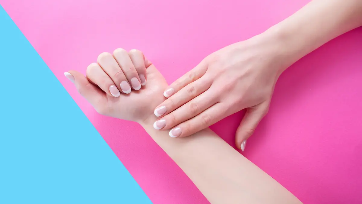Woman hands with french nails manicure style on pink and blue pastel background. Beauty and Manicure concept. Close up, selective focus