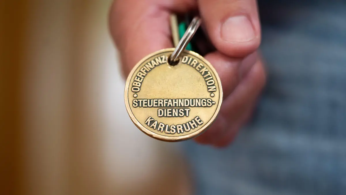 PRODUKTION - 17.08.2021, Baden-Württemberg, Stuttgart: ILLUSTRATION - Ein Steuerfahnder zeigt seine Dienstmarke (gestellte Szene). Die Steuerfahndung prüft verstärkt die Versteuerung von Airbnb-Einnahmen. Foto: Marijan Murat/dpa +++ dpa-Bildfunk +++
