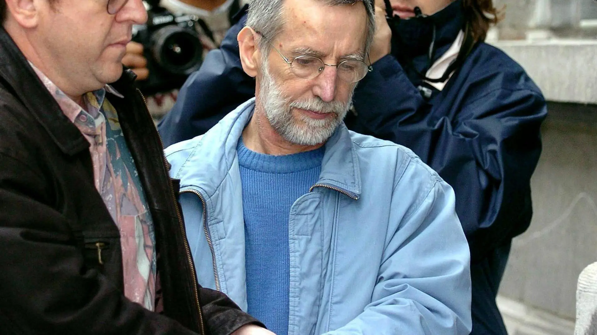 ARCHIV - 01.07.2004, Belgien, Dinant: Der französische Serienmörder Michel Fourniret (M) wird ins Gerichtsgebäude gebracht. In den französischen Ardennen startet die Polizei am 30.08.2021 erneut eine Suchaktion nach einem vor 18 Jahren verschwundenen Mädchen, das Opfer des Serienmörders Fourniret geworden ist. (zu dpa "Polizei sucht 2003 verschwundenes Opfer von Serienmörder") Foto: Boucau/BELGA/dpa +++ dpa-Bildfunk +++