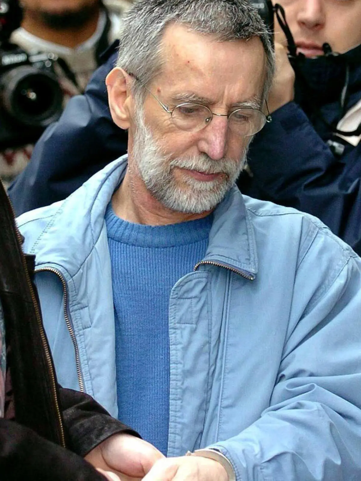 ARCHIV - 01.07.2004, Belgien, Dinant: Der französische Serienmörder Michel Fourniret (M) wird ins Gerichtsgebäude gebracht. In den französischen Ardennen startet die Polizei am 30.08.2021 erneut eine Suchaktion nach einem vor 18 Jahren verschwundenen Mädchen, das Opfer des Serienmörders Fourniret geworden ist. (zu dpa "Polizei sucht 2003 verschwundenes Opfer von Serienmörder") Foto: Boucau/BELGA/dpa +++ dpa-Bildfunk +++