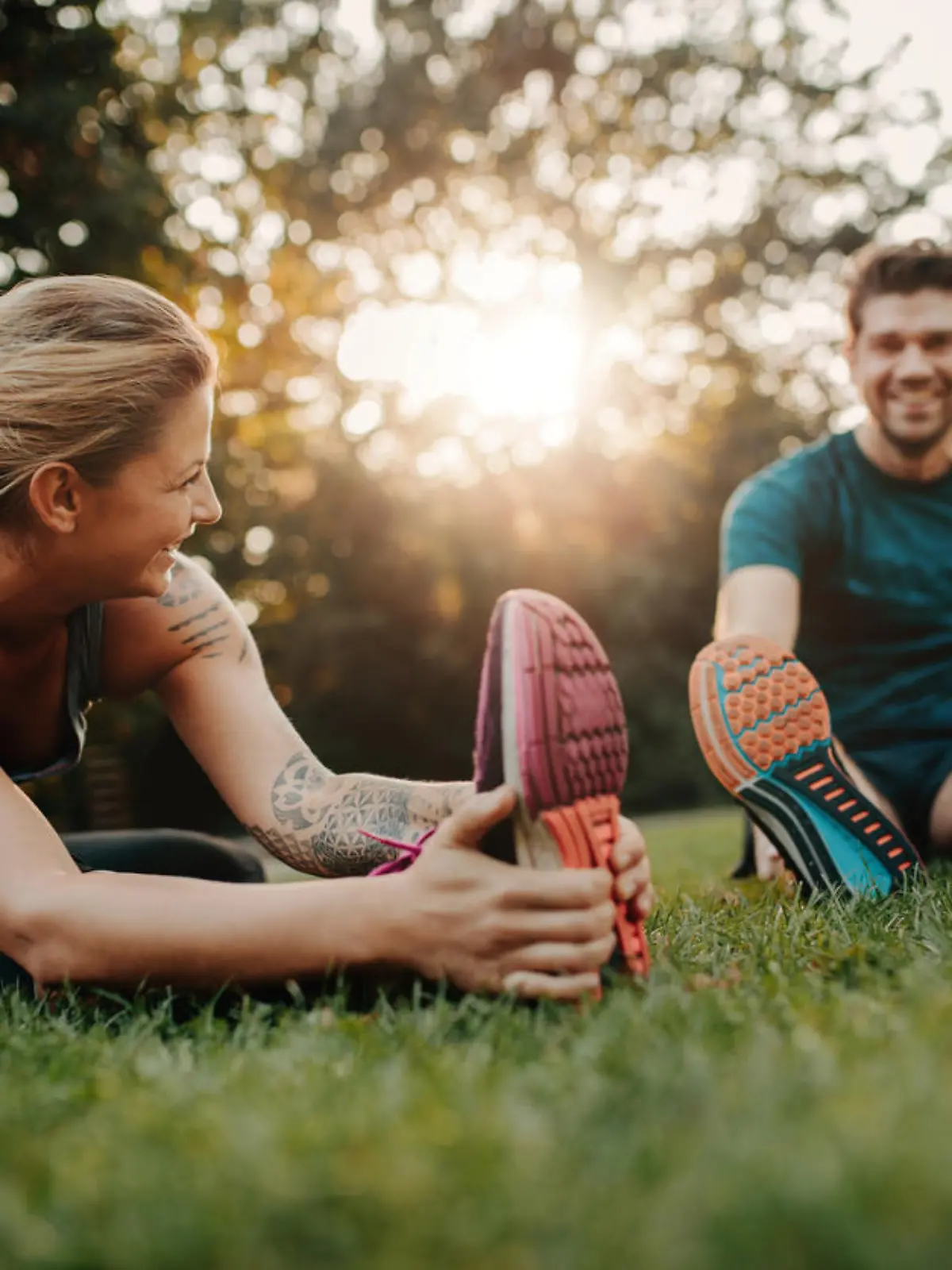 Fitness couple stretching outdoors in park. Young man and woman exercising together in morning.
