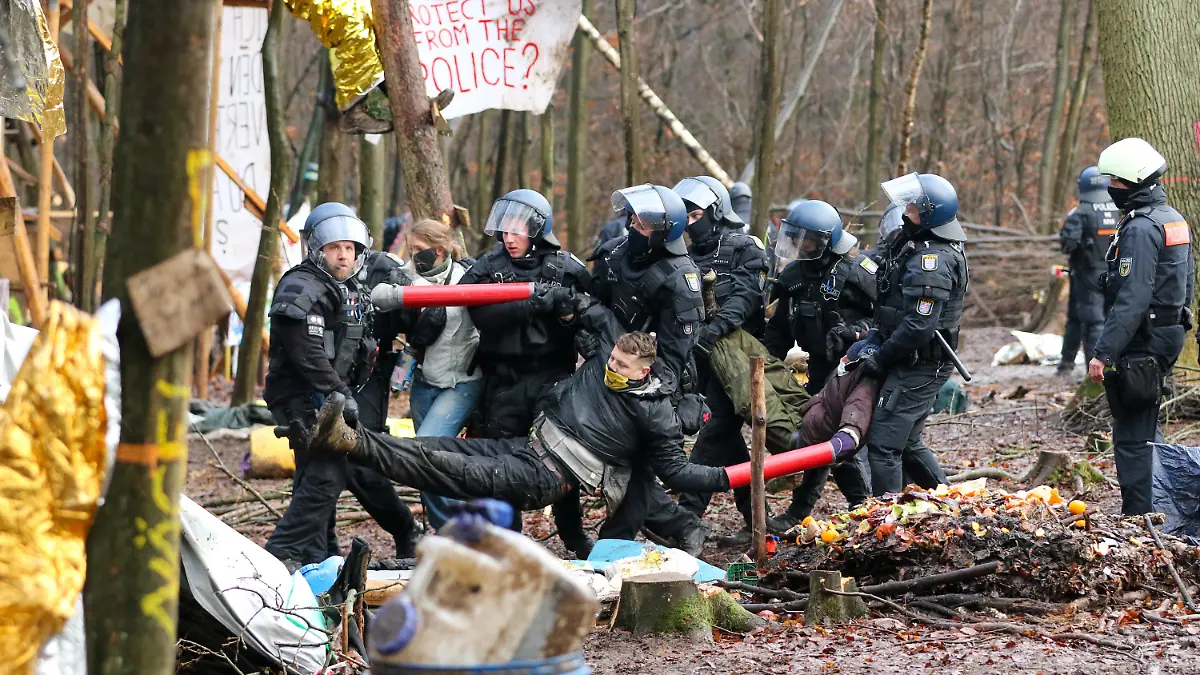 ARCHIV - 07.12.2020, Hessen, Dannenrod: Polizisten tragen drei Aktivisten, die ihre Arme in Metallrohre gesteckt und sich so miteinander verbunden haben, aus dem letzten verbliebenen Camp im Dannenröder Forst. (zu dpa "Einsatz im Dannenröder Forst: Ermittlungen gegen Thüringer Polizisten") Foto: Nadine Weigel/dpa +++ dpa-Bildfunk +++