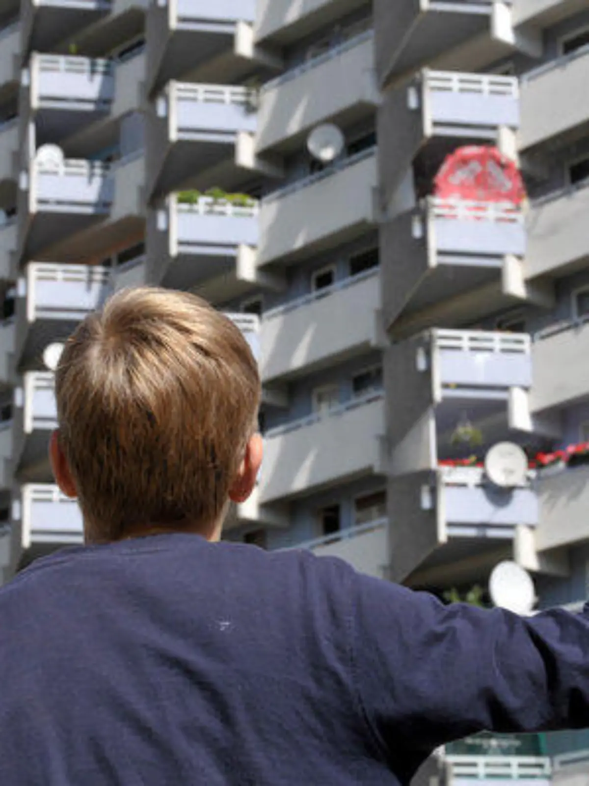 Neunjähriger Junge schaut zur Wohnung seiner Familie in einem Hochhaus hinauf, Trabantenstadt Chorweiler in Köln, August 2009. Köln, Nordrhein-Westfalen, Deutschland, 31.08.2009