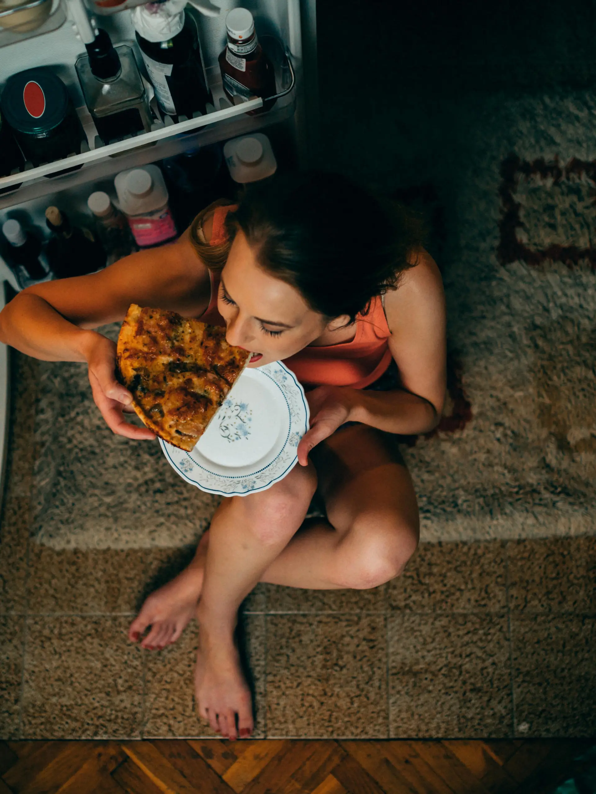 Woman eating in front of the refrigerator in the kitchen late night