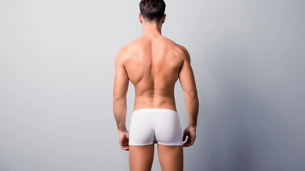 Back view photo of handsome confident guy with strong back and shoulders, wearing white underpants, isolated on grey background, copyspace