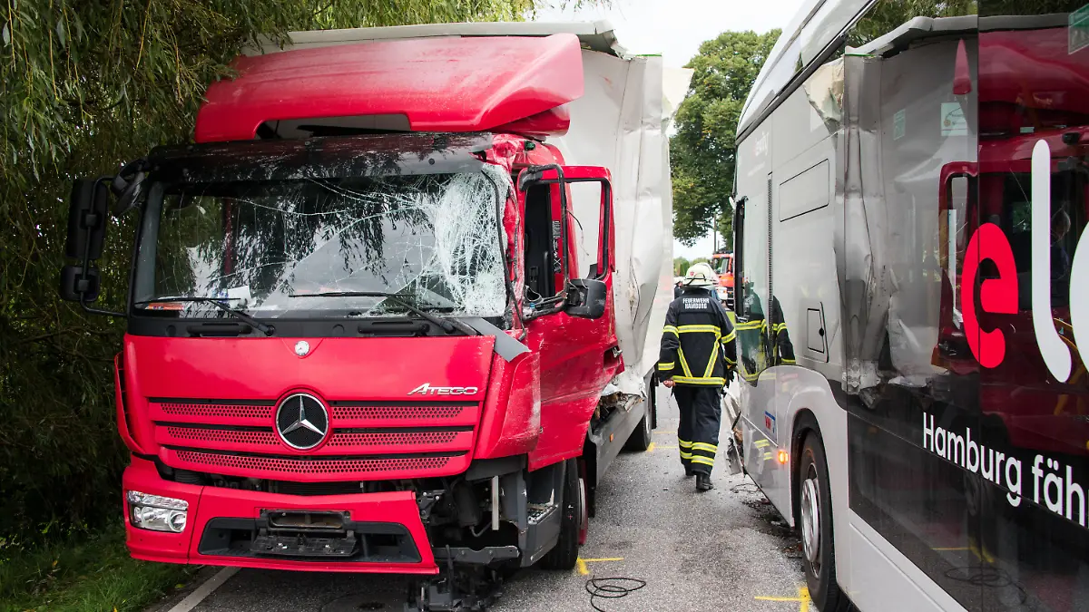 30.08.2021, Hamburg: Ein Lastwagen (l) und ein Schulbus stehen im Stadtteil Neuengamme an einer Unfallstelle. Bei dem Zusammenstoß zwischen dem Bus und dem LKW sind mehrere Schüler verletzt worden. Foto: Daniel Bockwoldt/dpa +++ dpa-Bildfunk +++