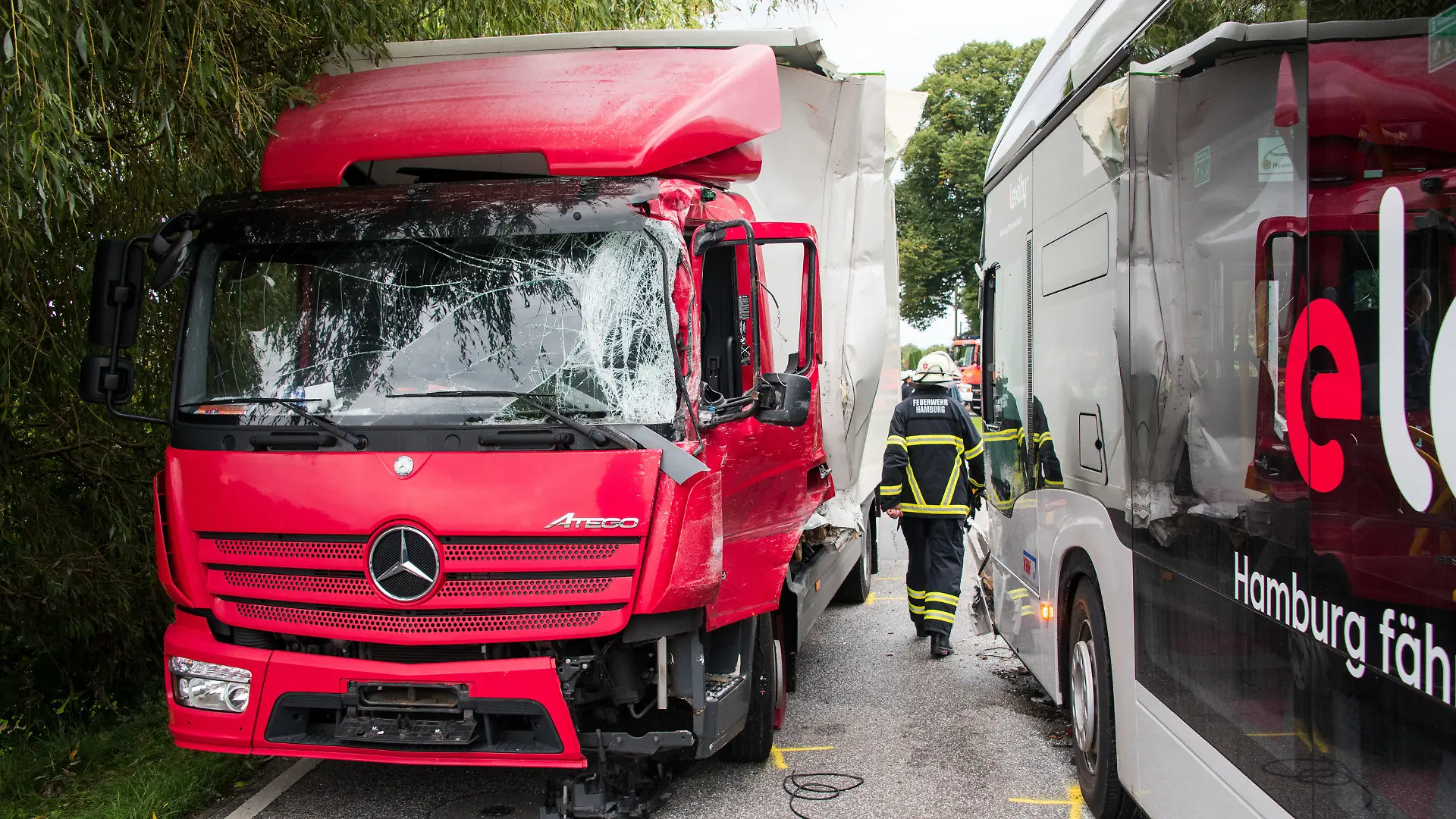 30.08.2021, Hamburg: Ein Lastwagen (l) und ein Schulbus stehen im Stadtteil Neuengamme an einer Unfallstelle. Bei dem Zusammenstoß zwischen dem Bus und dem LKW sind mehrere Schüler verletzt worden. Foto: Daniel Bockwoldt/dpa +++ dpa-Bildfunk +++