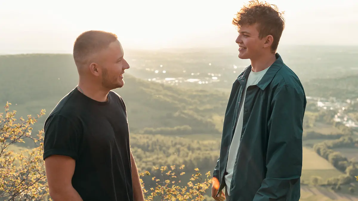 Student friends have a good time together outdoors. Talking, joking having fun in the sunset light on swabian alb mountain top. Outdoor summer youth lifestyle. South Germany.
