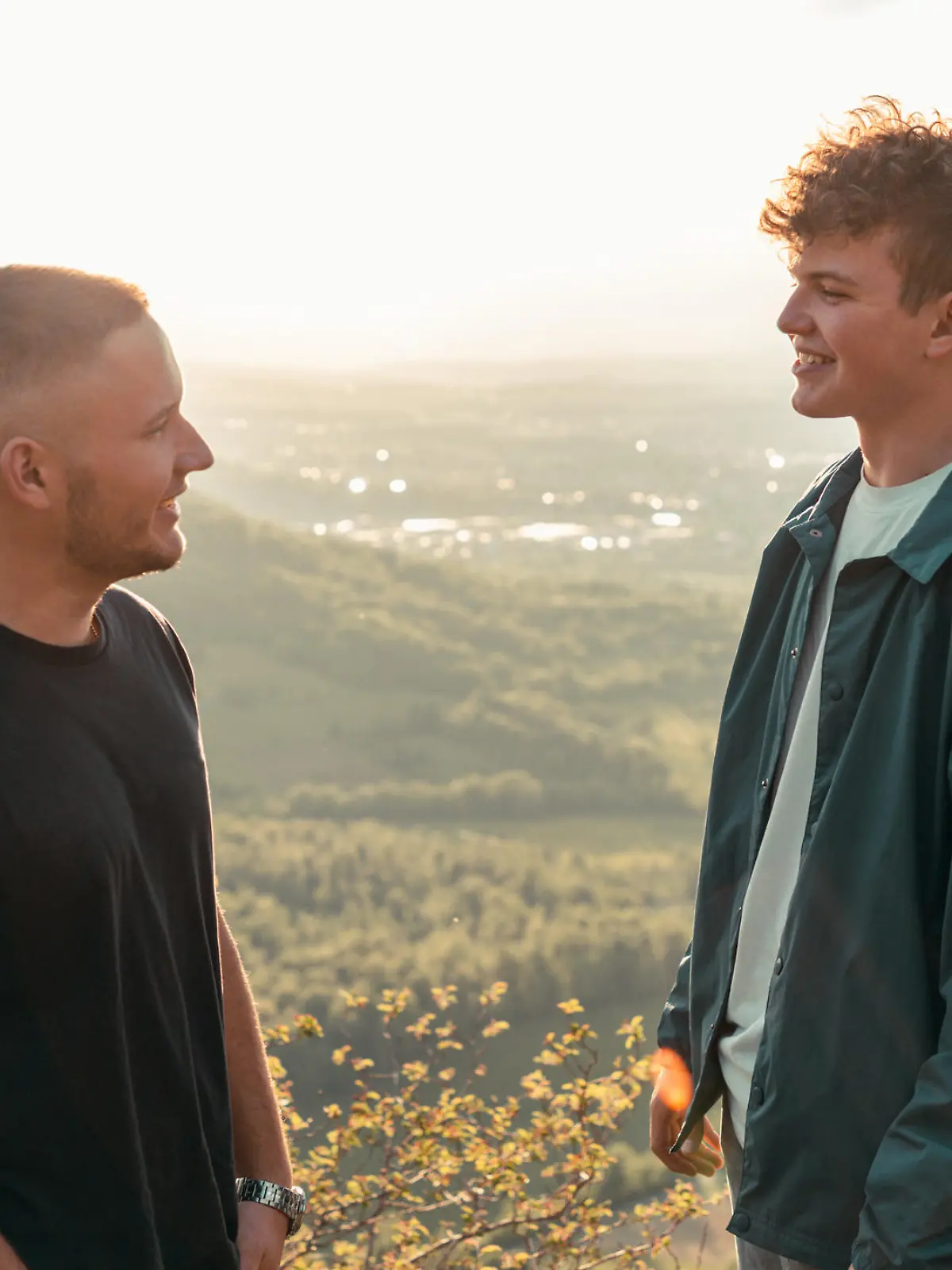 Student friends have a good time together outdoors. Talking, joking having fun in the sunset light on swabian alb mountain top. Outdoor summer youth lifestyle. South Germany.