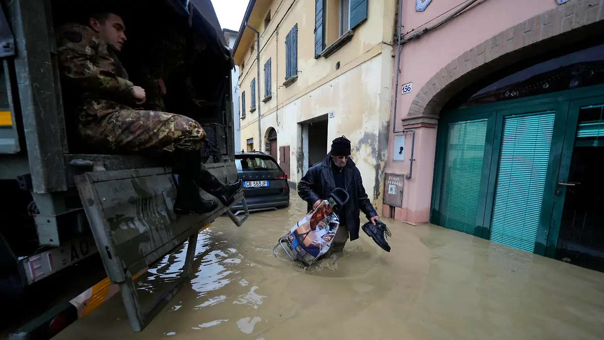 17.05.2023, Italien, Castel Bolognese: Ein Anwohner geht an einem Armeelastwagen in einem überschwemmten Dorf vorbei. Nach heftigen Regenfällen ist es in den italienischen Regionen Emilia-Romagna und den Marken zu teils dramatischen Überschwemmungen gekommen. Foto: Luca Bruno/AP/dpa +++ dpa-Bildfunk +++