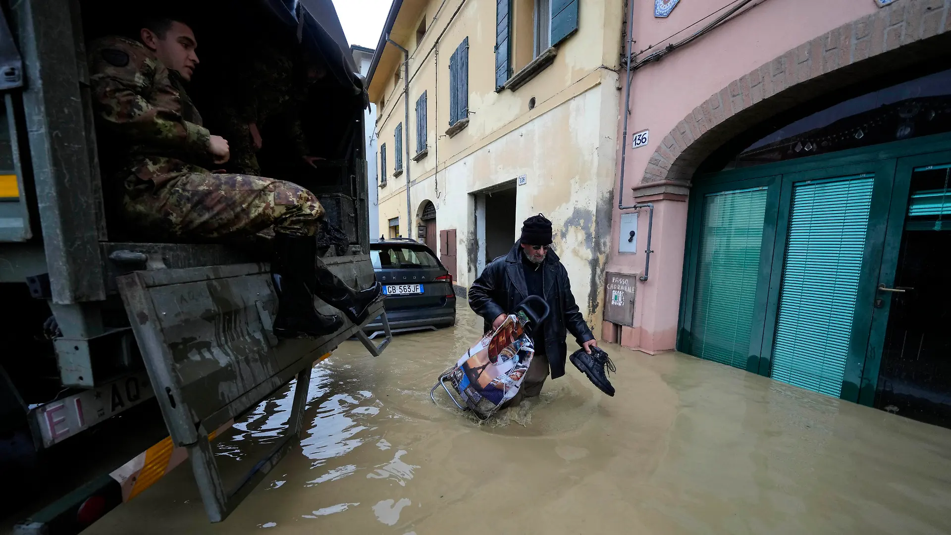 17.05.2023, Italien, Castel Bolognese: Ein Anwohner geht an einem Armeelastwagen in einem überschwemmten Dorf vorbei. Nach heftigen Regenfällen ist es in den italienischen Regionen Emilia-Romagna und den Marken zu teils dramatischen Überschwemmungen gekommen. Foto: Luca Bruno/AP/dpa +++ dpa-Bildfunk +++
