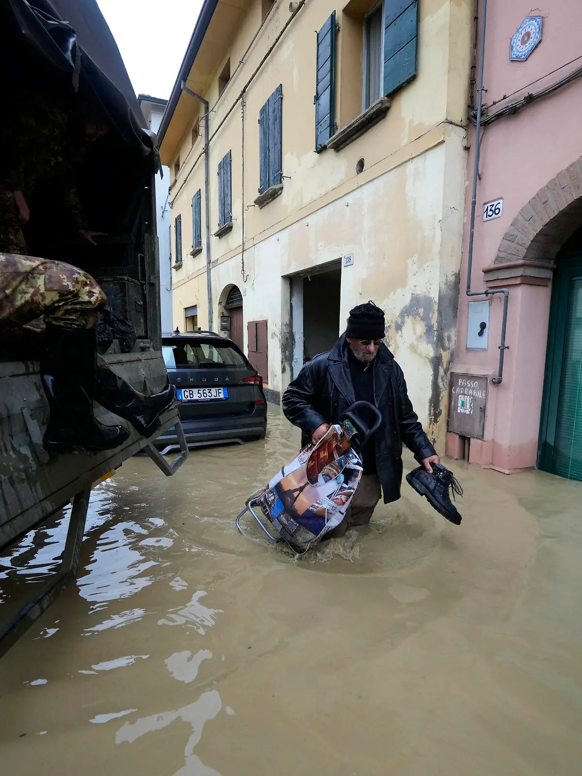 17.05.2023, Italien, Castel Bolognese: Ein Anwohner geht an einem Armeelastwagen in einem überschwemmten Dorf vorbei. Nach heftigen Regenfällen ist es in den italienischen Regionen Emilia-Romagna und den Marken zu teils dramatischen Überschwemmungen gekommen. Foto: Luca Bruno/AP/dpa +++ dpa-Bildfunk +++