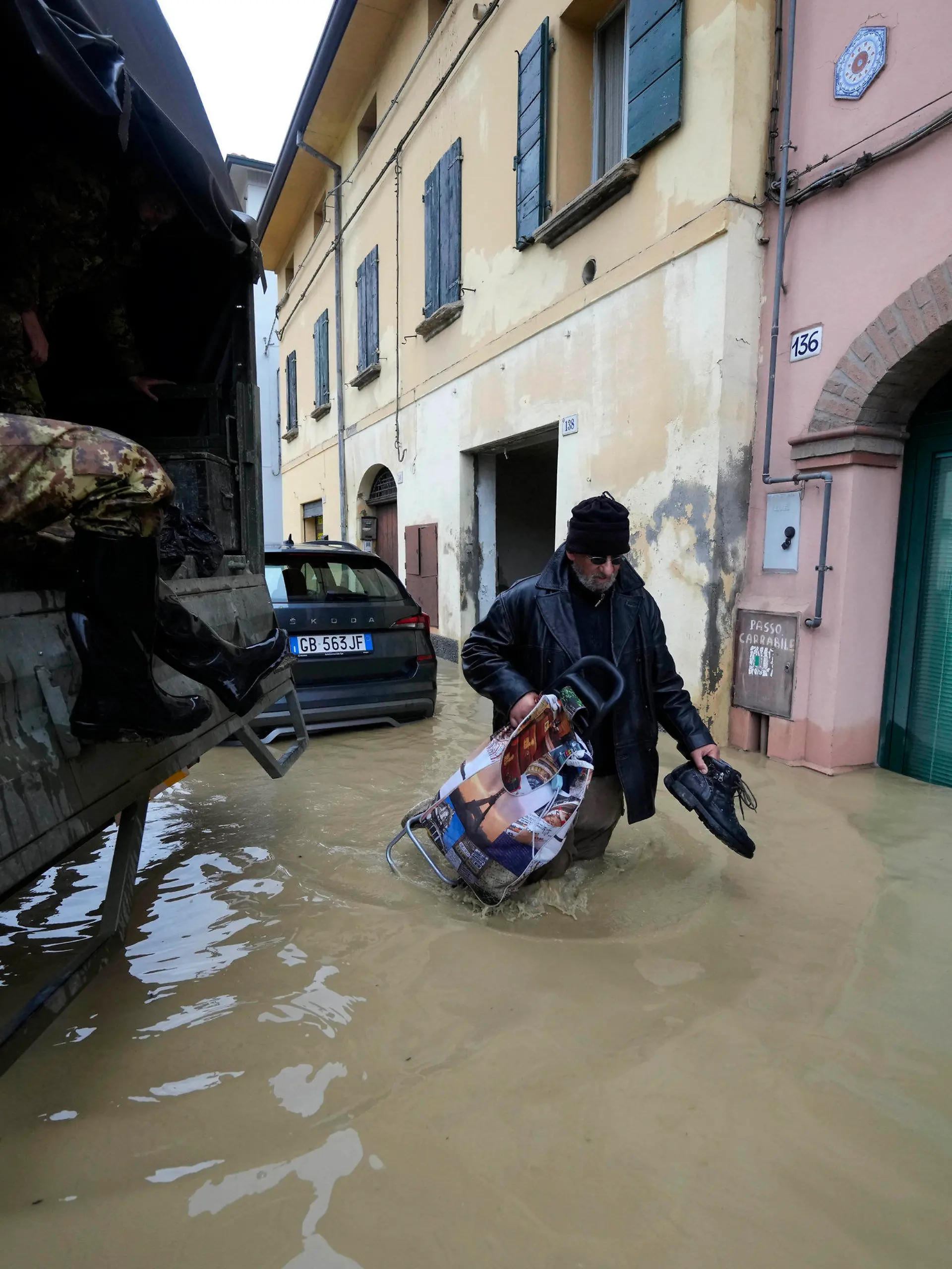 17.05.2023, Italien, Castel Bolognese: Ein Anwohner geht an einem Armeelastwagen in einem überschwemmten Dorf vorbei. Nach heftigen Regenfällen ist es in den italienischen Regionen Emilia-Romagna und den Marken zu teils dramatischen Überschwemmungen gekommen. Foto: Luca Bruno/AP/dpa +++ dpa-Bildfunk +++