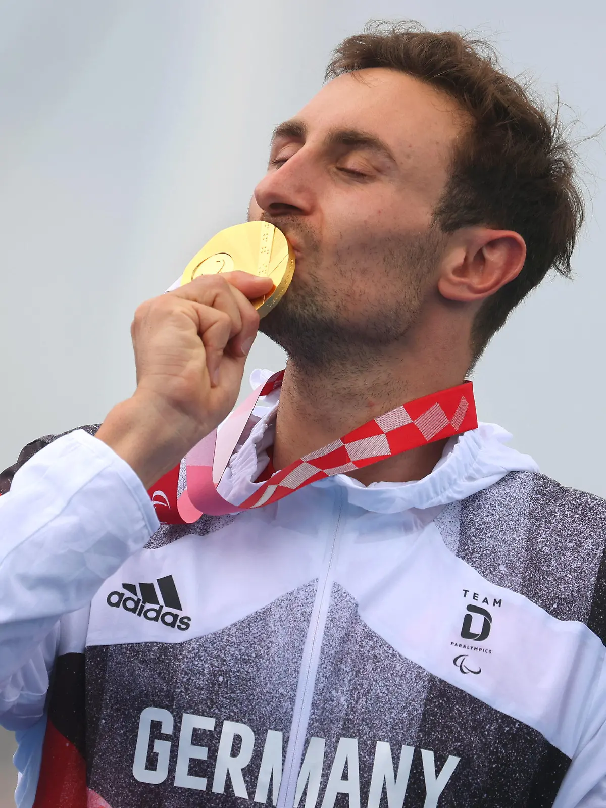 dpatopbilder - 29.08.2021, Japan, Tokio: Paralympics: Triathlon, Finale, Männer, Odaiba Marine Park. Martin Schulz aus Deutschland küsst bei der Siegerehrung die Goldmedaille. Foto: Karl-Josef Hildenbrand/dpa +++ dpa-Bildfunk +++