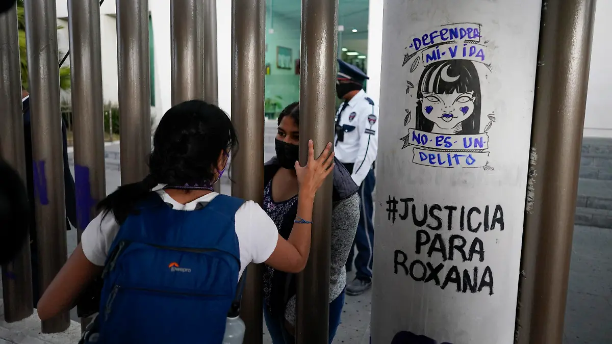 FILE - Roxana Ruiz, behind the gate, speaks from inside the court complex on the day of her court hearing where she is charged with killing her attacker in Chimalhuacan, State of Mexico, Mexico, April 18, 2022. Ruiz, who killed a man defending herself when he attacked and raped her in 2021 was sentenced to more than six years in prison, a decision her legal defense called “discriminatory” and vowed to appeal Tuesday, May 16, 2023.(AP Photo/Eduardo Verdugo, File)