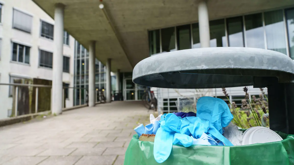 24.08.2021, Hessen, Darmstadt: Benutzte Einweg-Handschuhe liegen in einem Abfallbehälter vor dem Gebäude L201 auf dem Campus Lichtwiese der Technischen Universität (TU) Darmstadt. Am Tag zuvor waren hier sechs Menschen mit Vergiftungserscheinungen in Kliniken gebracht worden, ein 30 Jahre alter Student befand sich in einem kritischen Zustand. Wer die giftigen Stoffe in Lebensmitteln deponiert hat, ist unklar. Es wird wegen versuchten Mordes ermittelt. Foto: Frank Rumpenhorst/dpa +++ dpa-Bildfunk +++