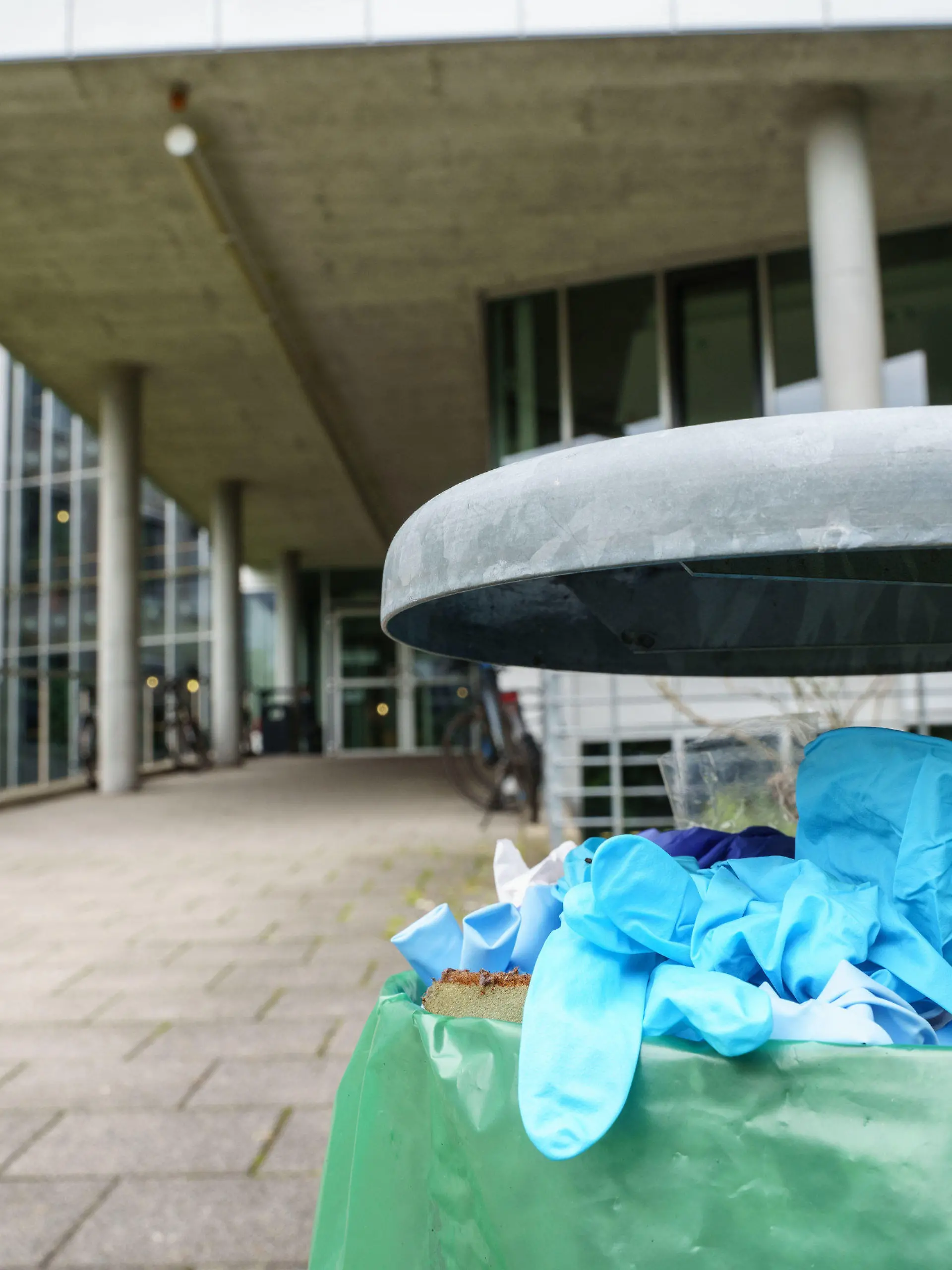 24.08.2021, Hessen, Darmstadt: Benutzte Einweg-Handschuhe liegen in einem Abfallbehälter vor dem Gebäude L201 auf dem Campus Lichtwiese der Technischen Universität (TU) Darmstadt. Am Tag zuvor waren hier sechs Menschen mit Vergiftungserscheinungen in Kliniken gebracht worden, ein 30 Jahre alter Student befand sich in einem kritischen Zustand. Wer die giftigen Stoffe in Lebensmitteln deponiert hat, ist unklar. Es wird wegen versuchten Mordes ermittelt. Foto: Frank Rumpenhorst/dpa +++ dpa-Bildfunk +++