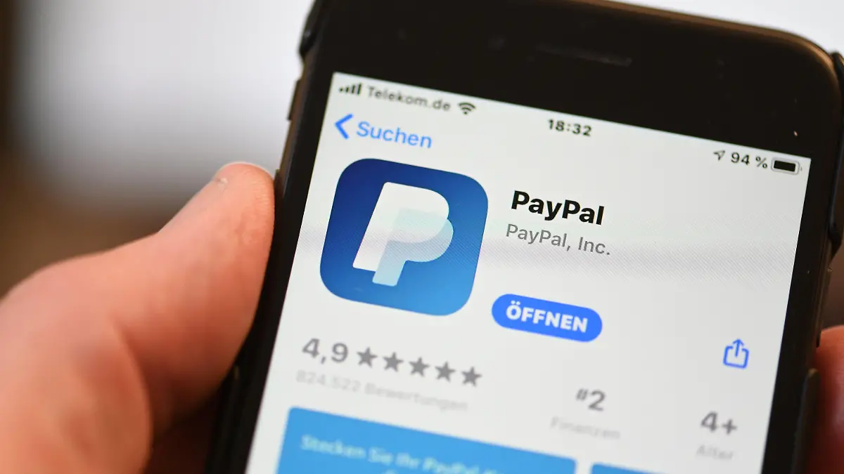 ARCHIV - 29.07.2020, Baden-Württemberg, Ravensburg: Die Applikation von PayPal ist auf einem Mobilfunkgerät zu sehen, das ein Mann in der Hand hält. Im zweiten Quartal legten die Erlöse im Jahresvergleich um 19 Prozent auf 6,2 Milliarden Dollar (5,2 Mrd Euro) zu, wie Paypal am Mittwoch nach US-Börsenschluss im kalifornischen San Jose mitteilte. Das gesamte abgewickelte Zahlungsvolumen wuchs um 40 Prozent auf 311 Milliarden Dollar. Dennoch brach der Gewinn angesichts deutlich höherer Ausgaben um 23 Prozent auf unter dem Strich 1,2 Milliarden Dollar ein. (zu dpa: «Paypal erleidet trotz starken Wachstums Gewinneinbruch ») Foto: Felix Kästle/dpa +++ dpa-Bildfunk +++